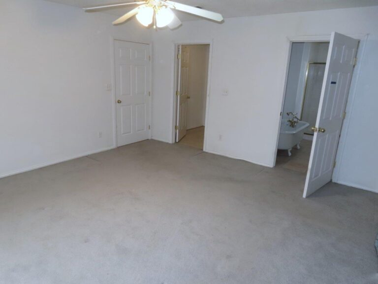 Empty bedroom with a ceiling fan and grey carpet. One door to the hallway. Next door on the right to a walk-in closet. Then the next door to the right is to the spacious master bathroom.